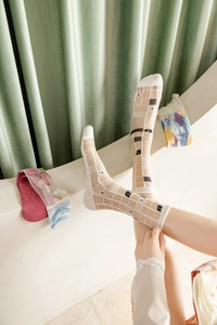 Détail de chaussettes en résille blanche avec broderies noires et motif à carreaux
