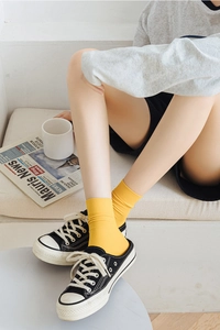Detailed view of yellow ribbed mid-calf socks styled with black canvas shoes