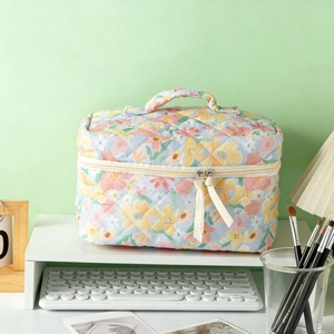 Quilted floral cosmetic bag with cotton fabric and ribbon detail on a vanity desk