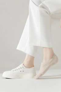 Detail of beige low-cut invisible socks worn with white sneakers for a seamless look