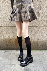 Close-up of black knee-high socks with diamond pattern and platform Mary Jane shoes