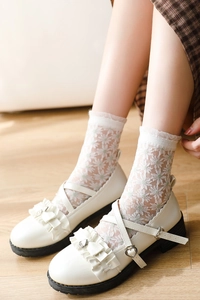 Détail de chaussettes en résille à marguerites avec chaussures Mary Jane à volants blancs