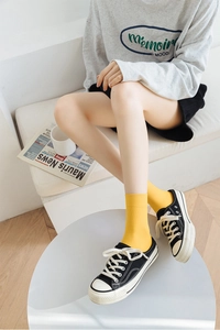 Close-up of bright yellow ribbed crew socks paired with black low-top canvas sneakers
