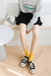 Close-up of bright yellow vertical stripe velvet crew socks styled with canvas sneakers