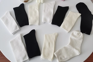 Close-up of ribbed cotton mid-calf socks in black and white on a minimalist table