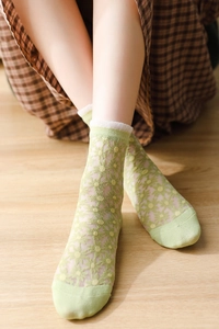 Gros plan de chaussettes transparentes vert clair avec broderies marguerites et dentelle