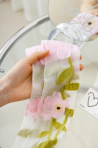 Detail of white sheer calf socks with pastel flower prints and breathable mesh texture