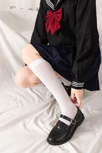 Détail d'une jupe plissée bleu marine avec chaussettes hautes blanches style uniforme