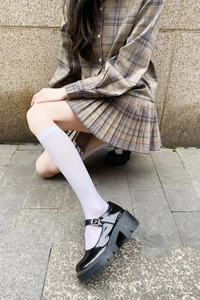 Detail view of white knee-high JK socks with subtle diamond pattern and Mary Jane shoes