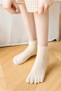 Close-up of beige hollow-out knit five-toe socks with elegant scalloped lace cuffs
