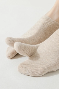 Close-up of beige knit low-cut socks featuring vertical ribbed texture on a foot model