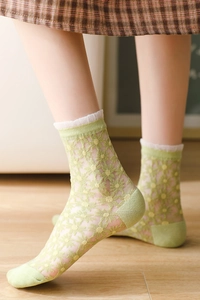 Gros plan sur chaussettes en résille vert clair avec broderies marguerites et dentelle