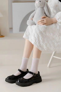 Detail of white lace ruffle cuffs and geometric mesh texture on mid-calf crew socks
