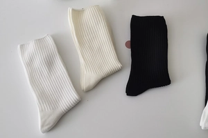 Detailed flat lay of three pairs of ribbed mid-calf socks in white, beige, and black