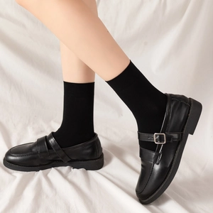 Détail de chaussures Mary Jane en cuir noir avec boucles et chaussettes de style JK