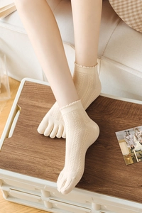 Detailed close-up of cream-colored mesh five-toe socks with elegant ruffled edges