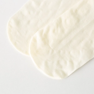 Macro view of cream-white knit fabric showing texture and stitching on the sock toe