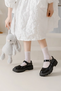 Close-up of black patent leather Mary Jane shoes with ruffled white lace crew socks