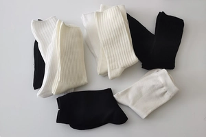 Detailed view of ribbed cotton mid-calf socks in black, white, and beige tones