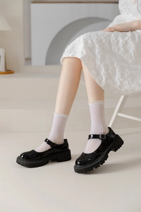 Close-up of black patent leather Mary Jane shoes with white lace frill crew socks
