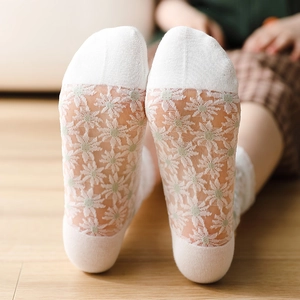 Détail de chaussettes en dentelle transparente à marguerites avec talon en coton doux