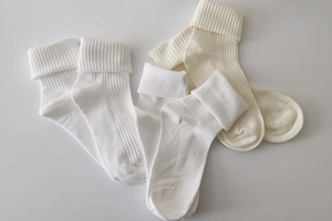 Detailed view of white ribbed knit socks featuring thick folded cuffs in a soft fabric