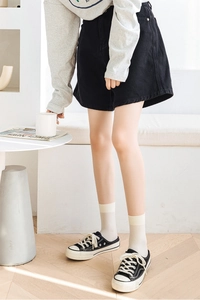Close-up of white velvet crew socks with vertical stripes worn with black canvas sneakers