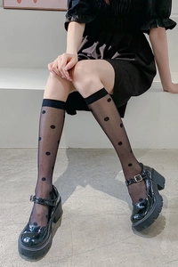 Detail of sheer black polka dot knee-high socks with wide elastic cuffs and Mary Jane shoes