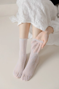 Close-up of white floral lace pattern and ruffle hem on these hollow mesh crew socks