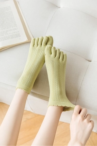 Macro detail of breathable light green hollow-out five-finger socks with ruffled edges