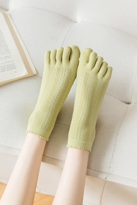 Close-up of light green five-toe socks with hollow mesh pattern and ruffled edges