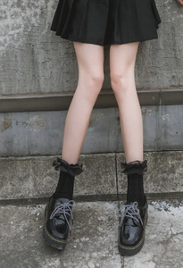 Detail of black Lolita lace ruffle socks styled with classic black platform loafers