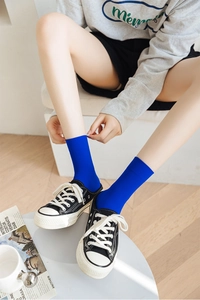 Detail of blue ribbed velvet mid-calf socks paired with classic black sneakers