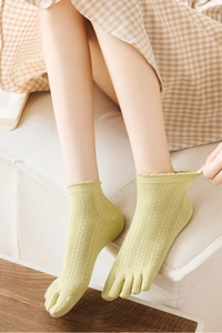 Close-up of light green lace-knit five-finger socks with elegant wavy ruffled cuffs