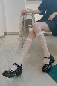 Detail of white polka dot sheer knee-high socks with black patent leather platform Mary Janes