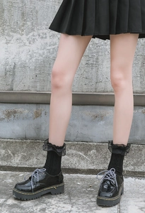 Detail of black Lolita socks with double-layered lace frills and leather platform boots