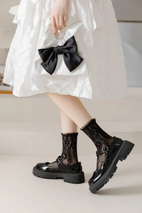 Detail of glossy black Mary Jane shoes paired with delicate floral lace socks
