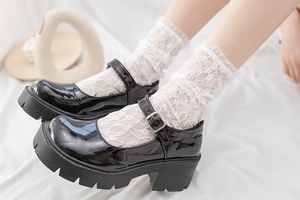 Détail de chaussettes Lolita en dentelle blanche avec des Mary Janes en cuir verni noir