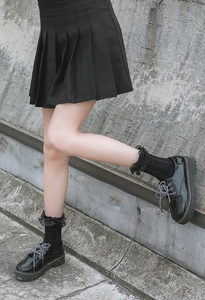 Close-up of black patent platform shoes with yellow stitching and lace socks