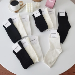 Classic black and white ribbed mid-calf knit socks in a minimalist home lifestyle setting