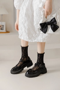 Close-up of black lace mid-calf socks paired with platform Mary Jane shoes and frill trim