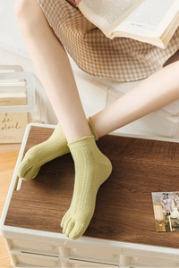 Detail of light green hollow-out mesh five-finger socks with elegant lace trim
