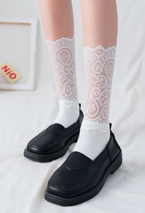 Détail de chaussettes blanches en dentelle avec motifs floraux et pointe en coton