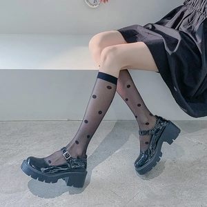 Detail of sheer black polka dot knee-high socks with glossy platform Mary Jane shoes
