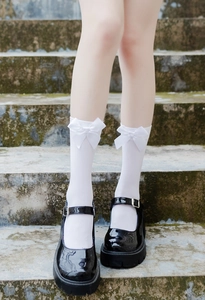 Close-up of white JK uniform knee-high socks with silk bow detail and Mary Jane shoes