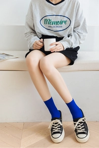 Close-up of royal blue ribbed knit mid-calf socks styled with black canvas sneakers