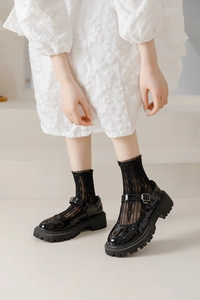Detail of black patent leather Mary Jane shoes with delicate lace mesh mid-calf socks