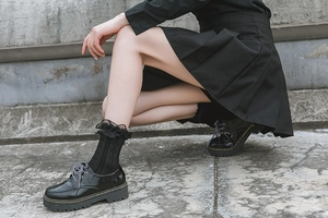 Close-up of black Lolita mid-calf socks with lace edges and heart cutouts with leather shoes