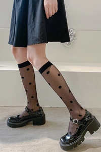 Detail of sheer black polka dot knee-high socks with wide non-slip cuffs and Mary Jane shoes
