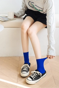 Detail showing elastic rib-knit texture of bright blue mid-calf velvet socks on model
